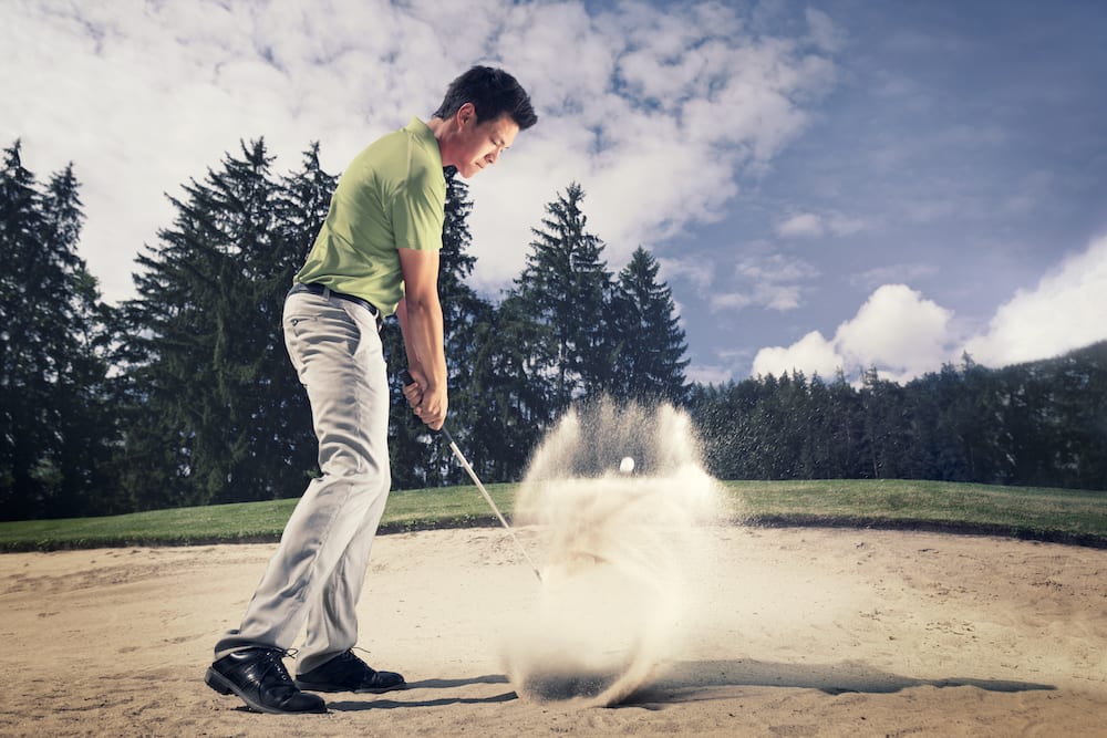 Male golfer hitting bunker shot